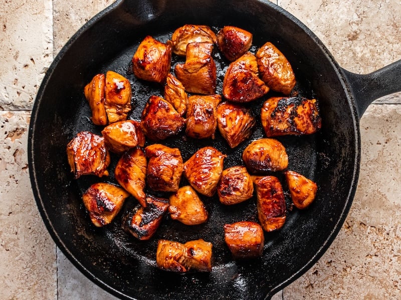Juicy, golden-brown chicken bites seared to perfection in a cast iron skillet after marinating in Paleovalley Organic Spice Blends.