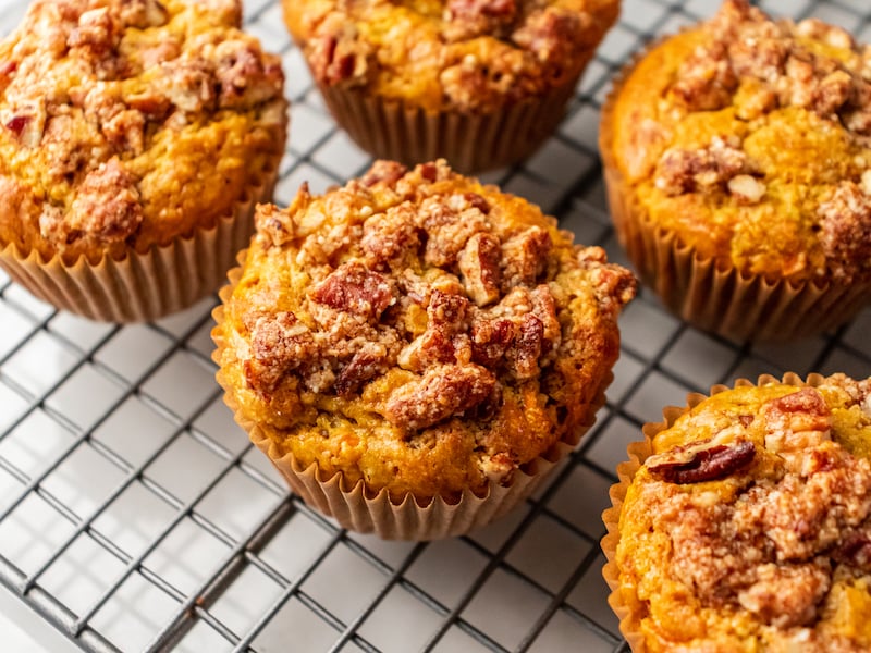 Healthy carrot cake muffins with a pecan streusel topping, cooling on a wire rack.