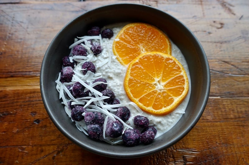 Chia seed pudding made with whey protein powder, topped with orange slices, frozen blueberries, and shredded coconut.