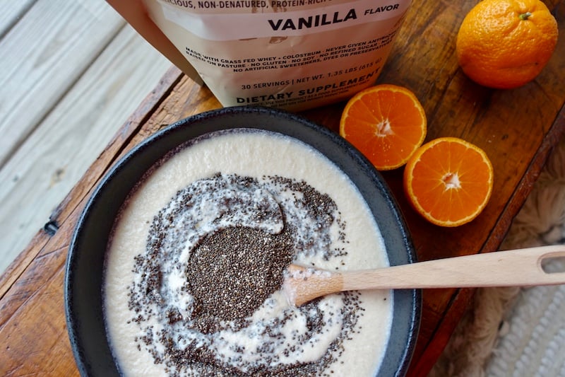 Bowl of chia pudding being stirred, made with chia seeds, fresh oranges, and Paleovalley grass fed whey protein powder.