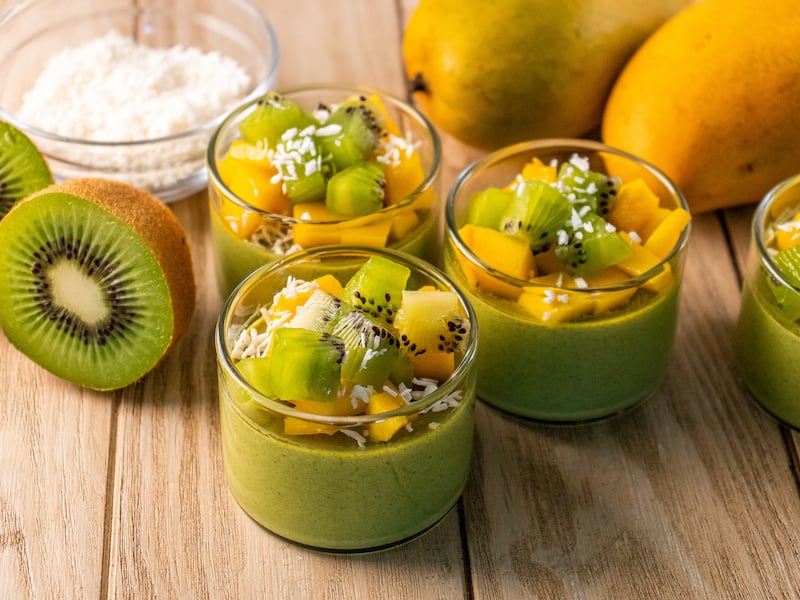 Dairy-free, sugar-free coconut milk panna cotta topped with fresh kiwi, mango, and shredded coconut, served in small glass cups.